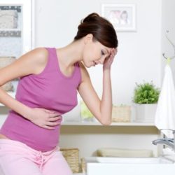 Pregnant woman with strong pain of stomach and nausea sitting in bathroom